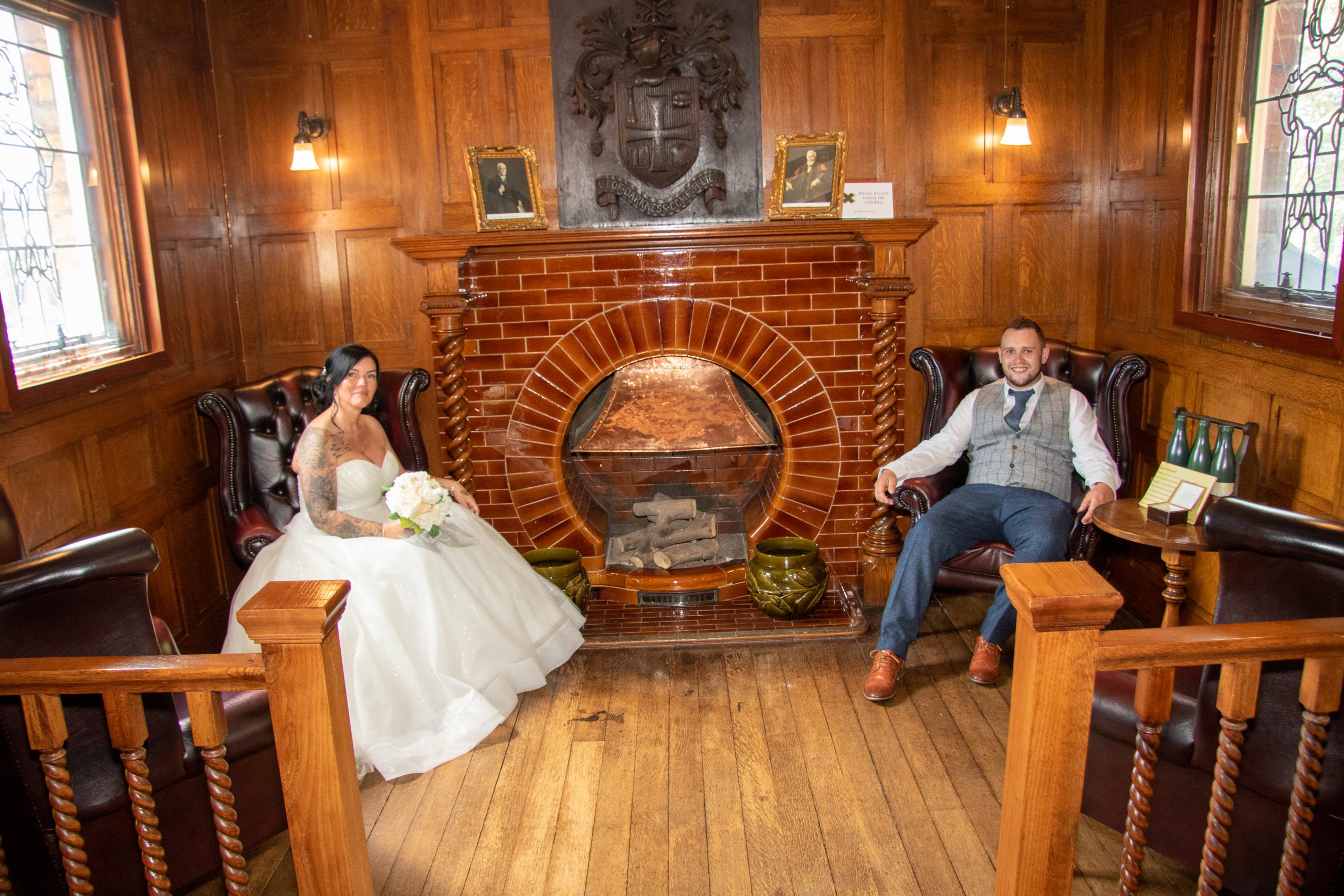 newly married couple posing for photographs next to an ornate fireplace
